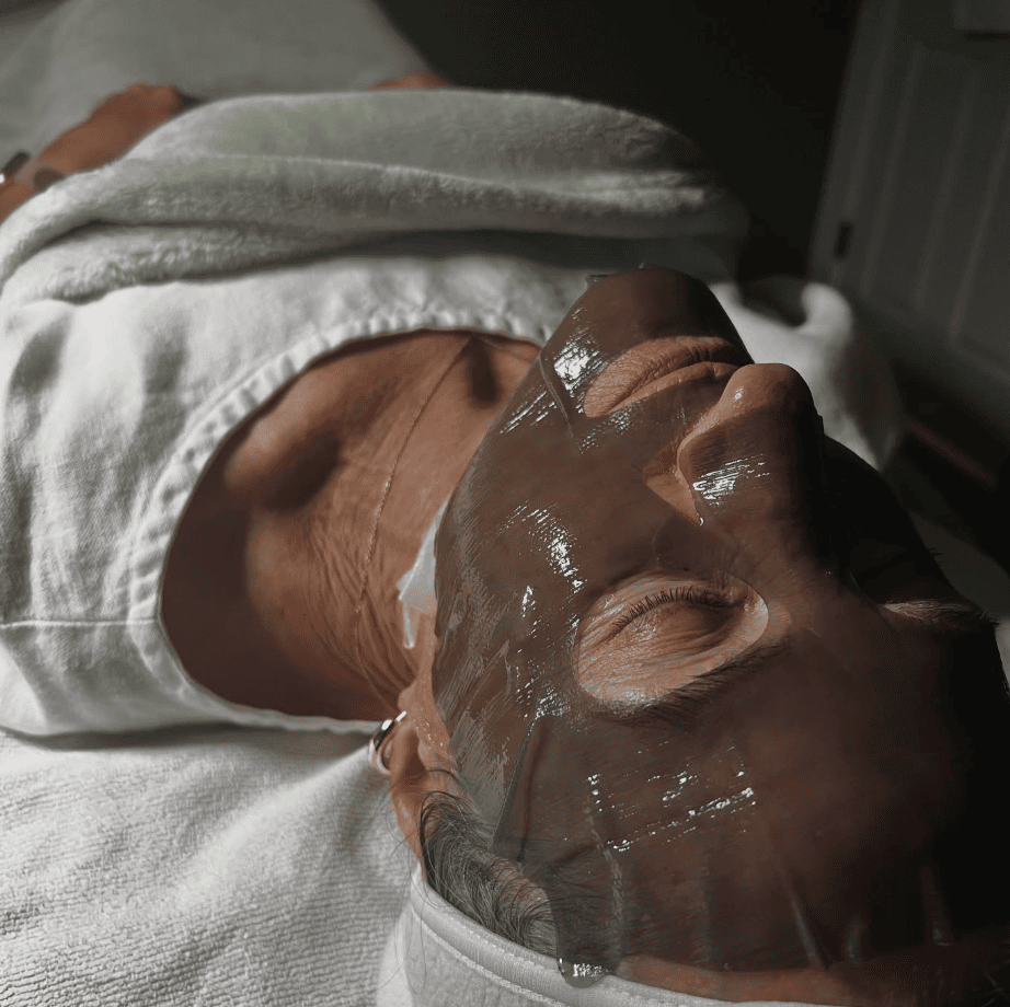 Client relaxing while receiving a professional-grade hydrating sheet mask facial at Pavona Parlor, a skincare studio in Beaufort SC